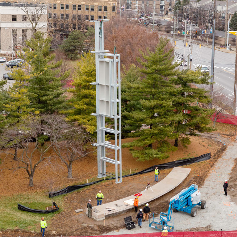 Construction workers place a piece of metal frame at a site on campus