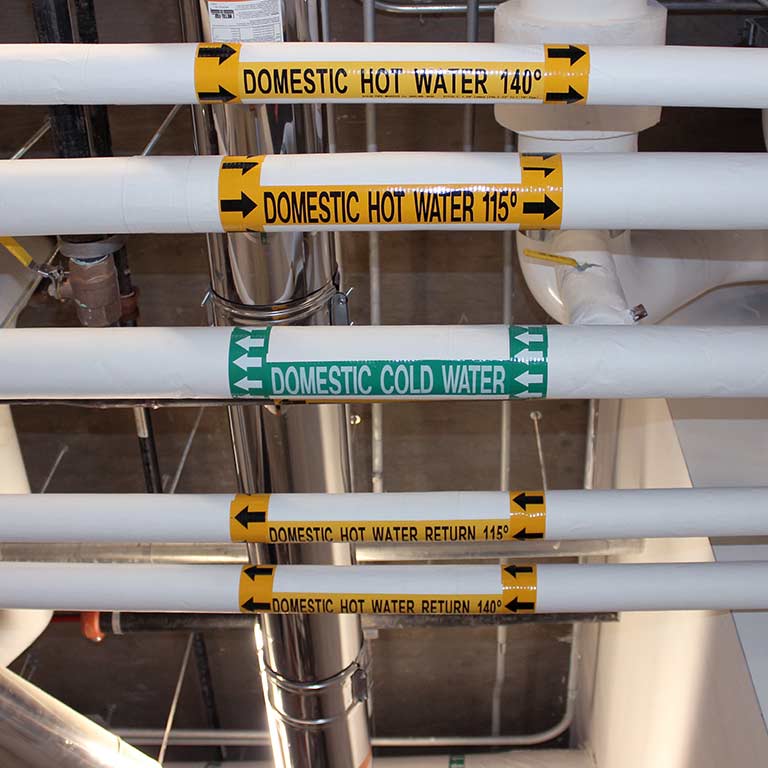 Hot and cold water pipes in a campus building utility room