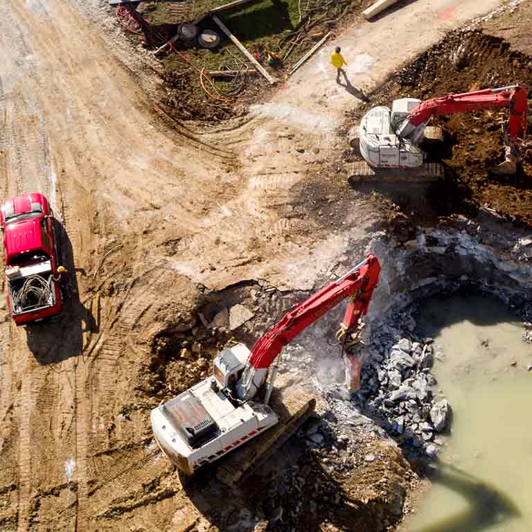 Workers use construction machinery to dig ground on a site. 